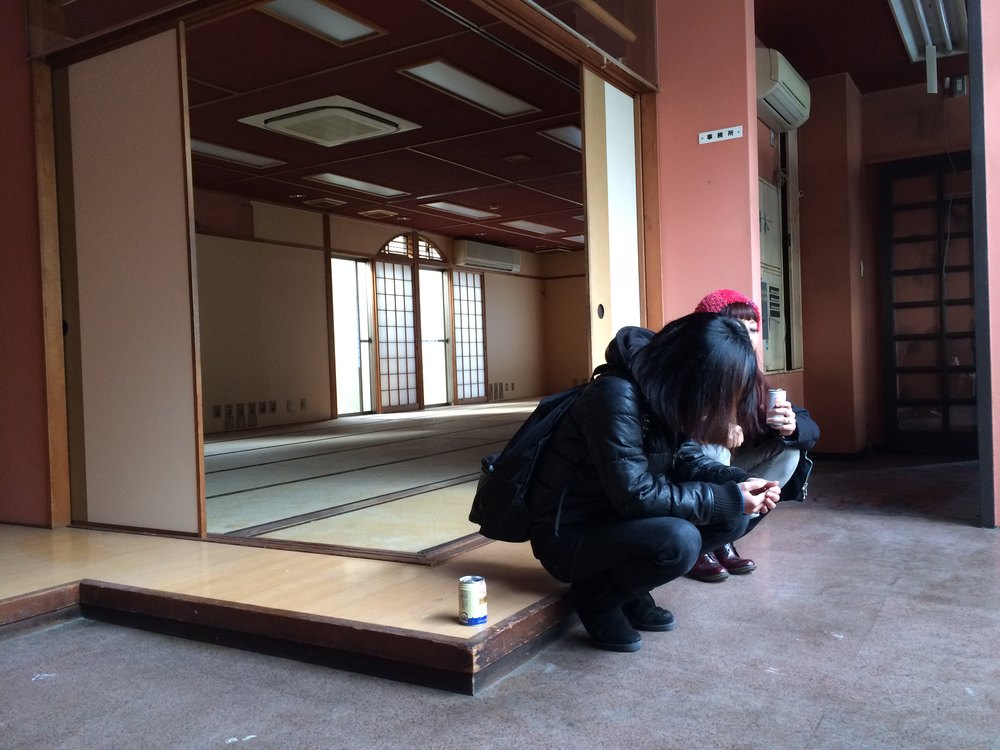 畳の入る前の和室。犬と一人のスタッフがしゃがんでいる