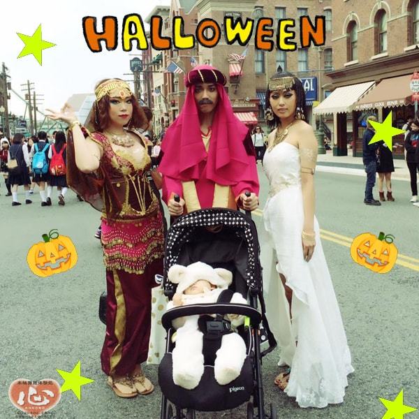 ハロウィンの飾りのある通りで、着飾った三人と乳母車