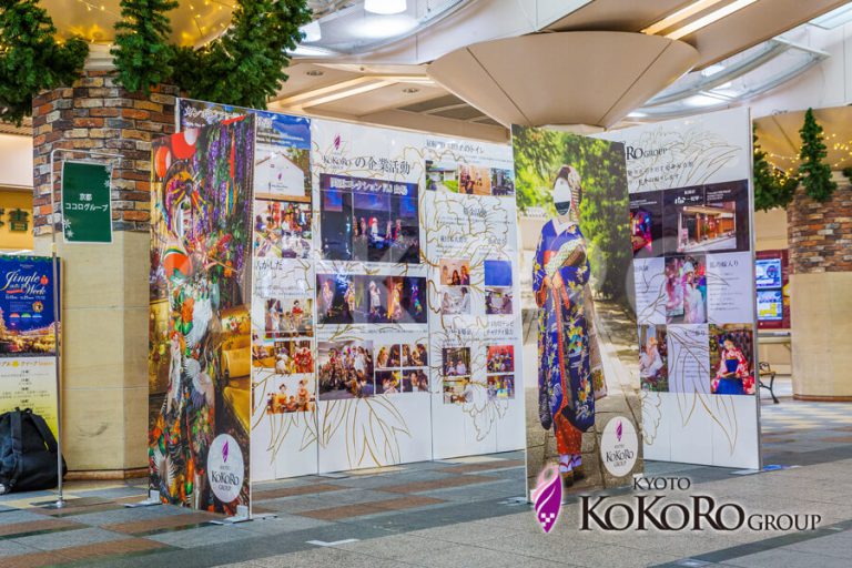 催しの会場。写真を並べた大きな壁の前に、衣裳が立つ