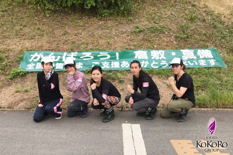 「がんばろう」の横断幕の前で、四人がしゃがんでいる
