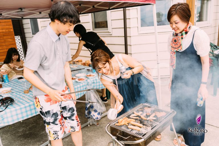 炭火の網を囲んで、三人が食べものを並べている