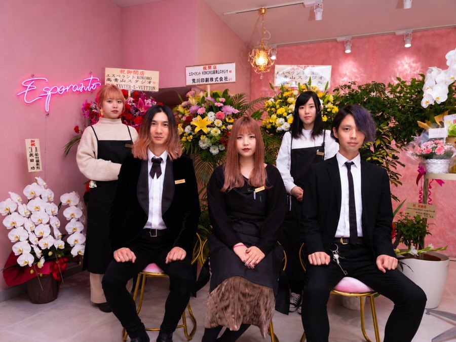 桃色の壁の新しいスタジオ。開店祝いの花に囲まれてスタッフ五人