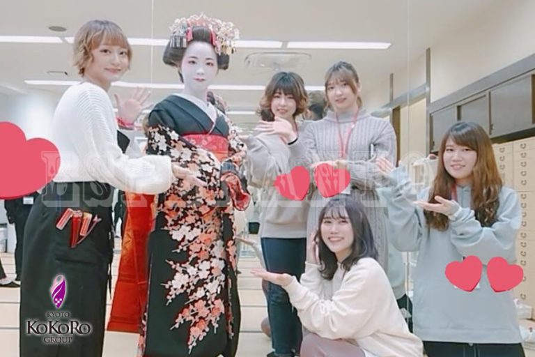 教室で、舞妓姿の人を囲んで学生と並ぶ